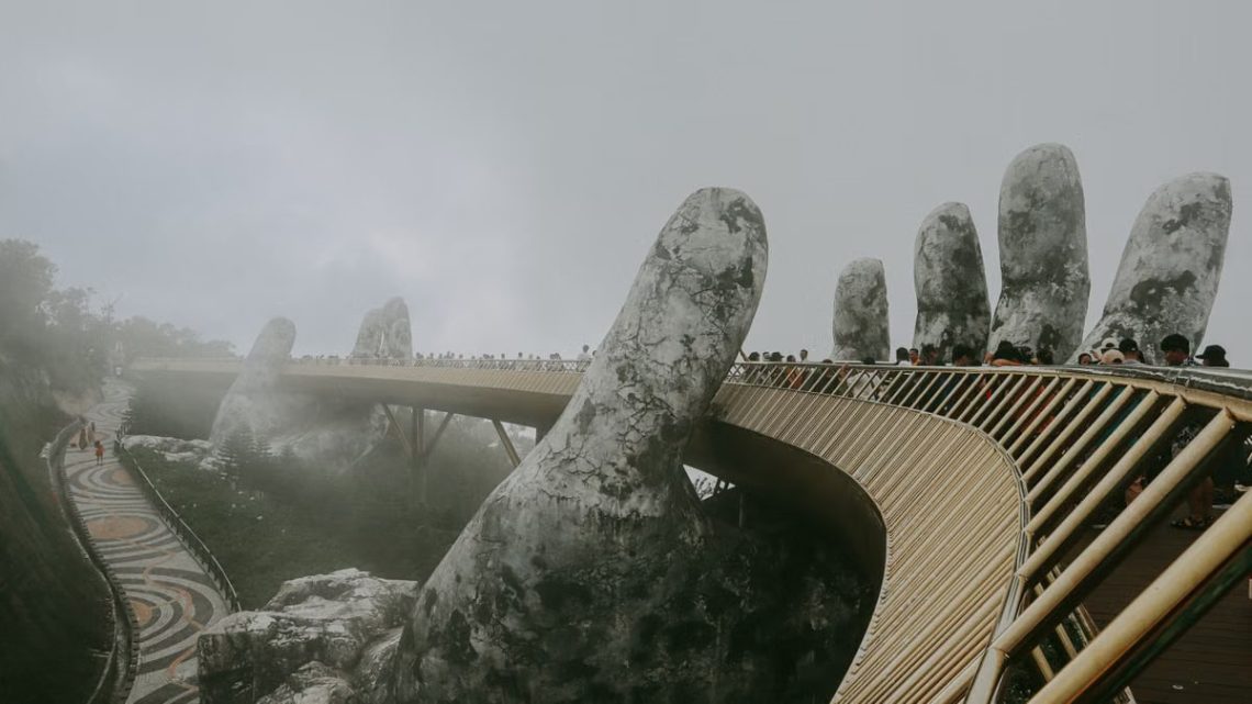 Stunning view of Golden Bridge held by stone hands enveloped in mist, Ba Na Hills.