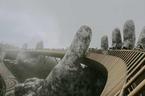 Stunning view of Golden Bridge held by stone hands enveloped in mist, Ba Na Hills.